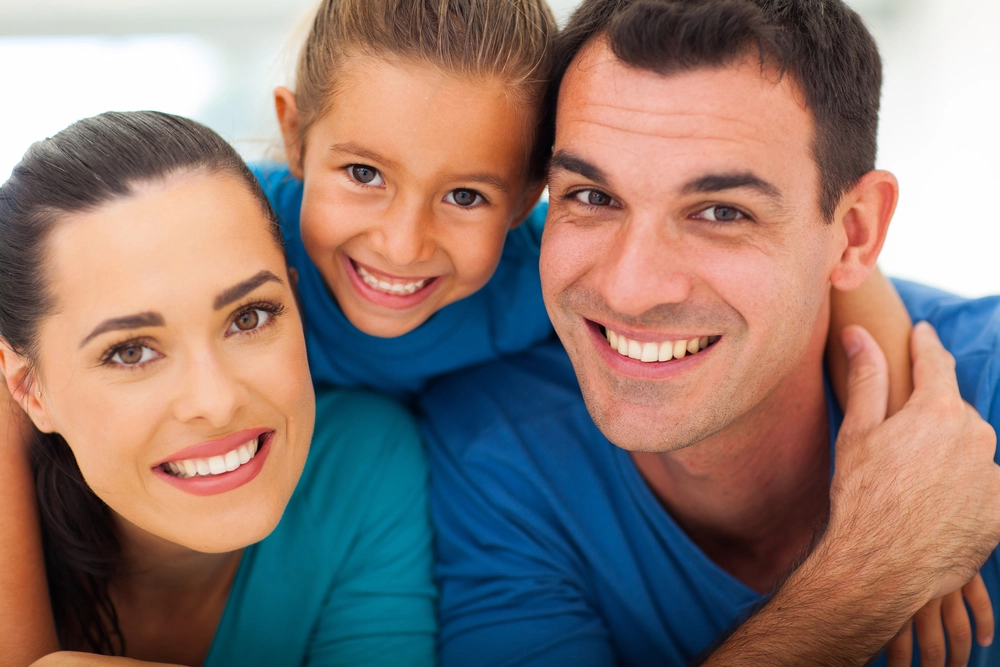 couple with child looking at camera and smiling - dental services